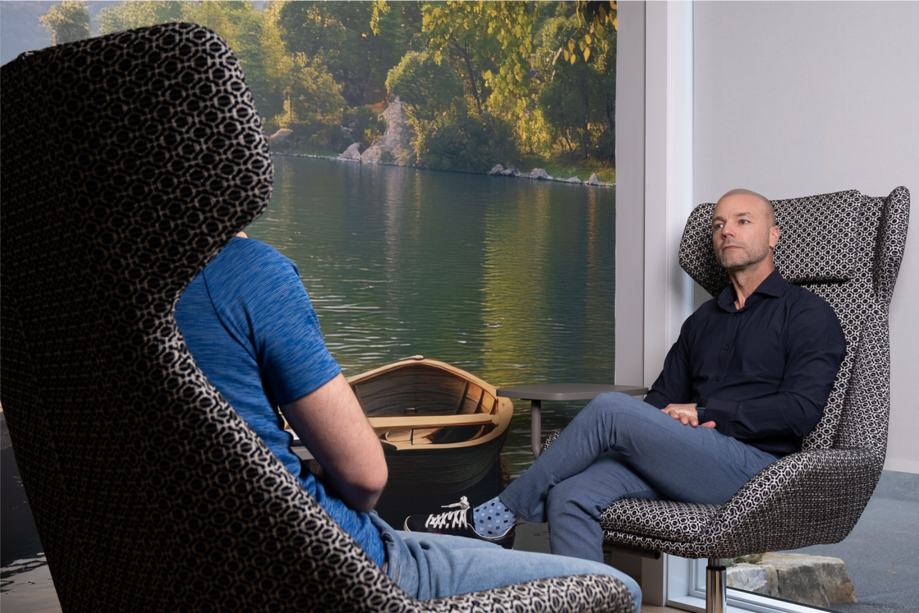 Espace de thérapie · deux fauteuils face à face devant un grand mural d'un lac et d'une chaloupe